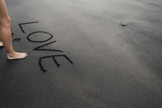 Person writing love on black sand benijo beach tenerife