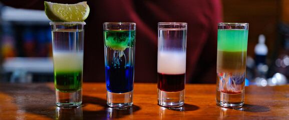 Vibrant layers of colorful shots display a creative mixology masterpiece. Each glass captures light beautifully while showcasing a spectrum of colors, igniting excitement in lively bar atmosphere.