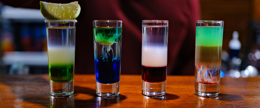 Vibrant layers of colorful shots display a creative mixology masterpiece. Each glass captures light beautifully while showcasing a spectrum of colors, igniting excitement in lively bar atmosphere.