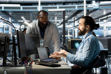 Team of computer scientists using PC in server farm, analyzing data. Team working data center office staff members examining infrastructure, ensuring system integrity and security