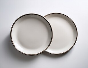 two white ceramic plates are arranged side by side on a white surface the plates have a simple round shape with a slightly raised rim