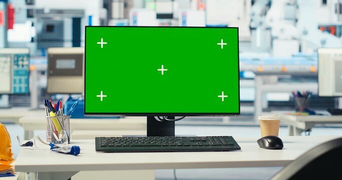 Isolated screen PC in photovoltaics factory used to monitor performance of robot arms manufacturing solar panels. Chroma key mockup computer in empty facility used to inspect solar plant machinery