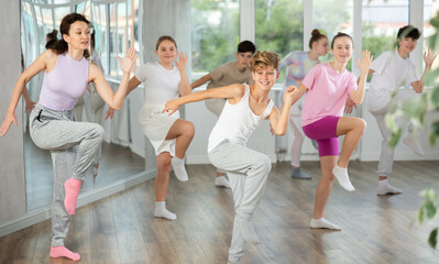 Naklejka premium Group of boys and girls rehearsing dancehall dance in studio