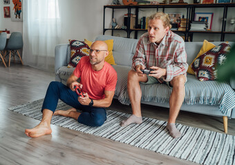 Father and son enjoying emotional gaming session comfortable living room sofa sharing playful expression bonding through interactive electronic entertainment highlighting warm family values connection