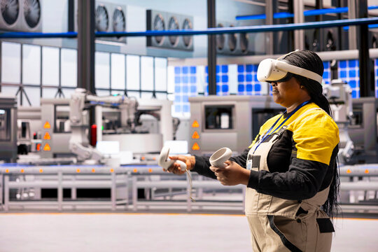 Female engineer wearing VR headset examines data insights to improve operational efficiency in smart factory. Technician using virtual reality in Industry 4.0 facility equipped with advanced sensors.