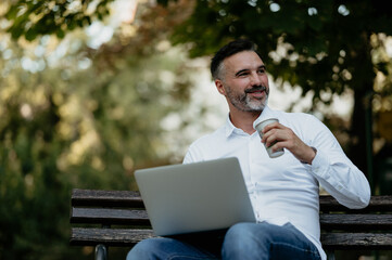 Mature man relaxing working remotely in park