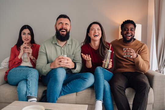 Diverse friends laughing together on sofa at home