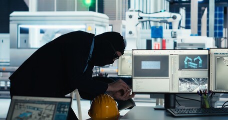 Hacker sneaking into solar panel facility, inserting USB stick into PC to steal secret manufacturing data. Thief bypasses photovoltaics factory security, extracting company files, camera B