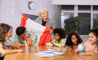 listening to teacher s story about Peru, child examines this country on globe