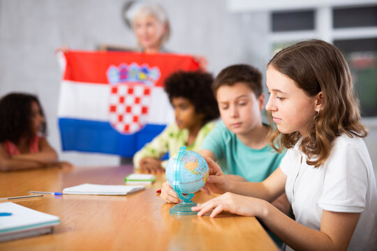 at evening geography lesson, elderly teacher tells students about Croatia and shows flag of this country