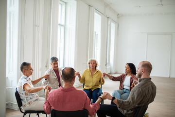 Adults and seniors calmly meditating in support circle at community center