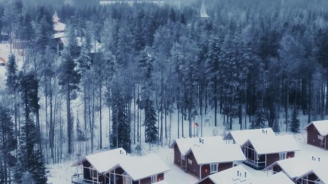 View of a snow-covered coniferous forest with some cottages among them. Aerial view. 4K.
