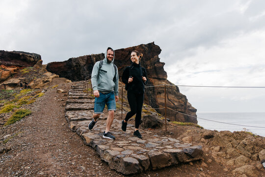Active couple enjoying a scenic hike on rocky terrain, surrounded by dramatic cliffs and ocean views, embodying the spirit of adventure and exploration in nature