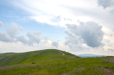 Fototapeta premium Peaceful mountain scene featuring lush green hills, distant ranges, and a bright blue sky with white clouds. Ideal for nature, travel, and outdoor lifestyle imagery. Carpathian Mountains, Ukraine
