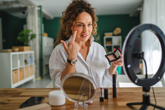 Woman recording makeup tutorial using smart phone and ring light