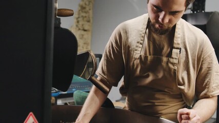 Artisan roaster skillfully prepares fresh coffee beans in a cozy roasting space during the afternoon hours
