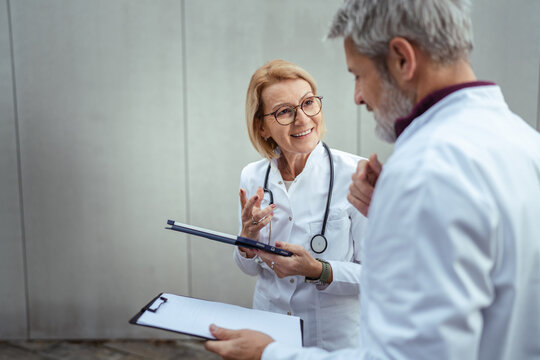 Doctors discussing patient information holding medical clipboards