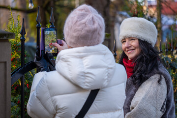 Two women enjoying a joyful moment outdoors, capturing memories together while walking in nature, surrounded by greenery and fresh air, celebrating friendship and aging gracefully