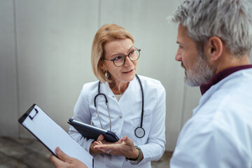 Doctors discussing patient information holding medical clipboards