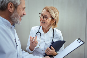 Mature doctors discussing medical report during consultation