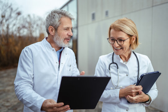 Healthcare professionals discussing patient data using laptop outdoors
