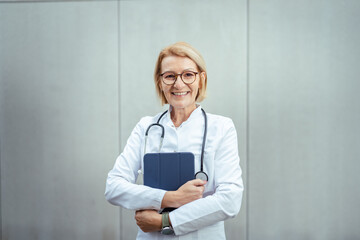 Smiling senior female doctor holding digital tablet