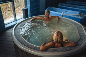 Couple relaxing in hydrotherapy hot tub bath at spa