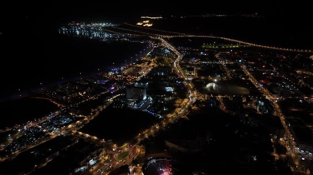 Aerial night view of Agadir city, Morocco, showing illuminated streets, coastal lights, and the iconic &ldquo;God, Homeland, King&rdquo; hill landmark.