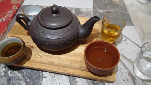Ceramic teapot and teacups arranged on wooden tray ready for service