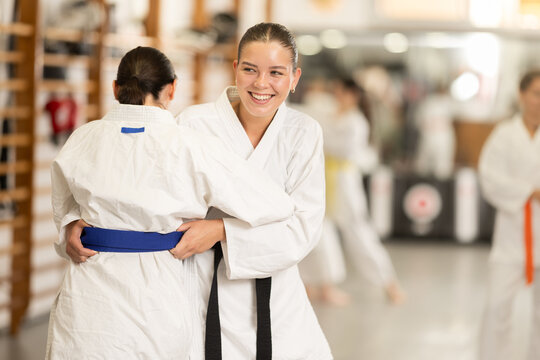 Young women athletes in white kimonos practice judo wrestling. Training at Academy of Martial Arts hand-to-hand combat. Athletes compete in strength and agility, and practice judo combat..... - Powered by Adobe