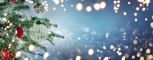 Christmas tree with red and silver decorations on blue background with bokeh, glowing. Merry Christmas and Happy New Year greeting card. Xmas and Winter holidays. Christmas wide banner