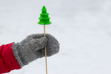 Man holding a lollipop in the shape of a spruce tree.The concept of celebrating Christmas.