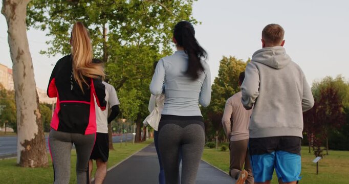 Team of young people men and women running in the park having sport jog workout outdoors. Group of runners training in nature jogging together. Fitness concept. 4k video. Slow motion video.