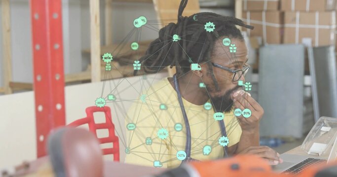 Working man with dreadlocks in yellow T-shirt studying laptop at workshop with stethoscope overlay