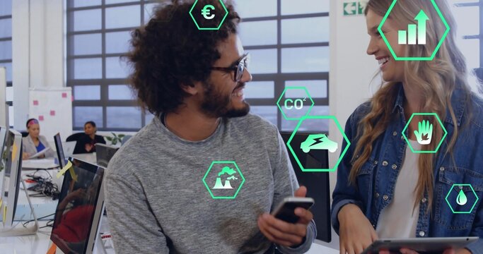 Talking coworkers in gray sweater and denim jacket with phone and tablet in office, green overlays - Powered by Adobe