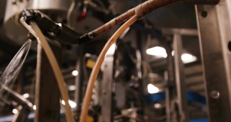 Showing translucent yellow hoses and insulated wires crossing factory floor, with metal posts