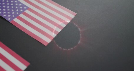 Fototapeta premium Lying upper paper American flag reflecting lens flare on dark table with partial flag, copy space