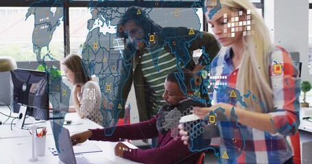 Four coworkers wearing business attire pointing at laptop monitors and map overlay in open office
