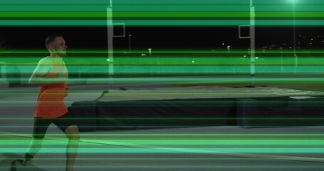 Striding runner orange top dark shorts on night track with mat and green streaks, copy space