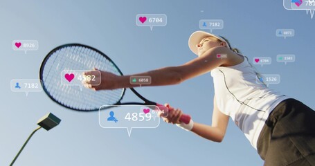 Swinging tennis player holding racket on court wearing visor and tank top showing hearts
