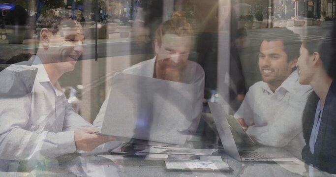 4 colleagues biz casual discussing laptops and docs at table by window reflecting sidewalk planters - Powered by Adobe