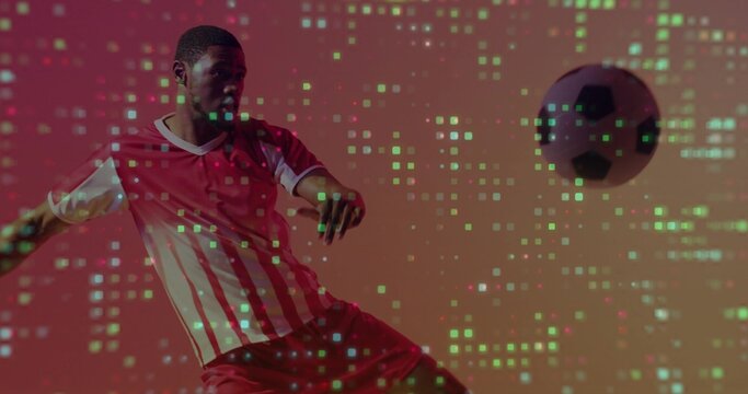 Kicking adult player in red-striped jersey red shorts striking ball in studio with green pixelation