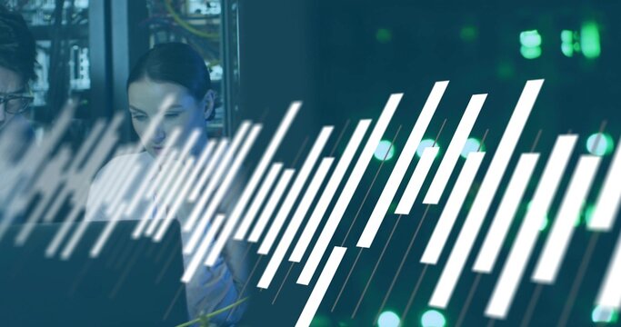 Female technician wearing coat monitoring network on laptop in data center, with white graphic bars