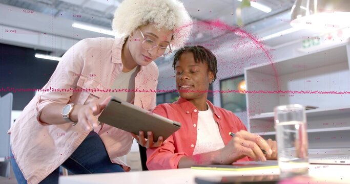 Leaning woman pink shirt and man coral shirt discussing tablet at office desk with data overlay