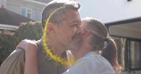 Woman placing left hand over man's sparking yellow particle ring around ringed hands for wedding ad