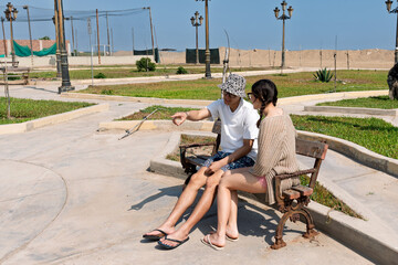Young couple enjoying conversation on park bench near beach