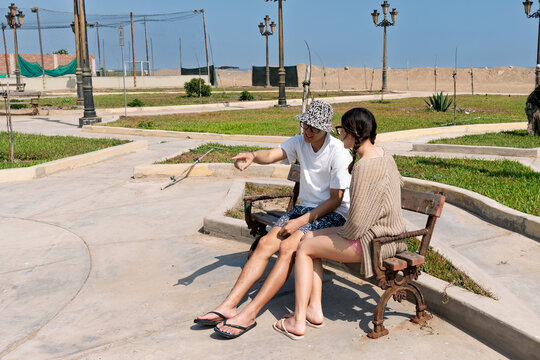 Young couple enjoying conversation on park bench near beach - Powered by Adobe