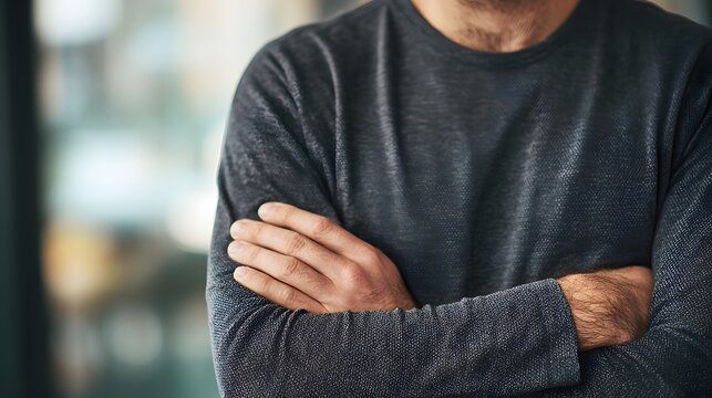 Close-up of a man with his arms crossed, showing a sense of contemplation or seriousness.