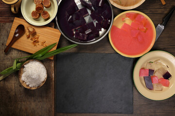 Traditional Malaysian desert Nonyah Kuih making preparing ingredients panadn leaf shredded coconut gula melaka  agar agar sagu spread over black slate messy rustic wood