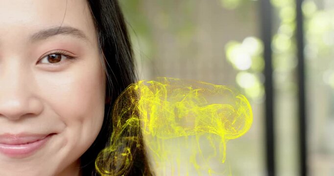Woman opening one eye, smiling as yellow vapor forms and swirls beside cheek for beauty commercial